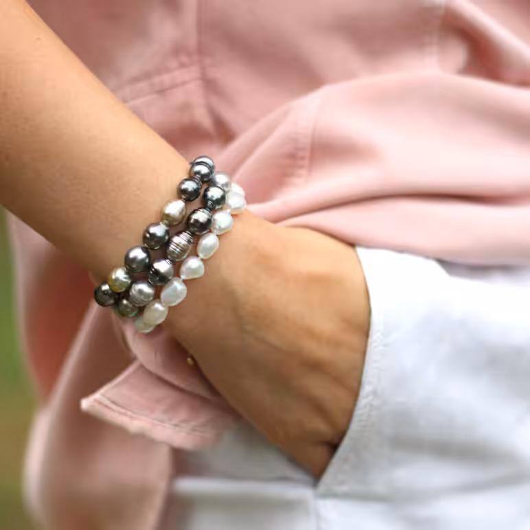 A lifestyle product image, featuring a woman wearing stacked Zara Tahitian pearl bracelets