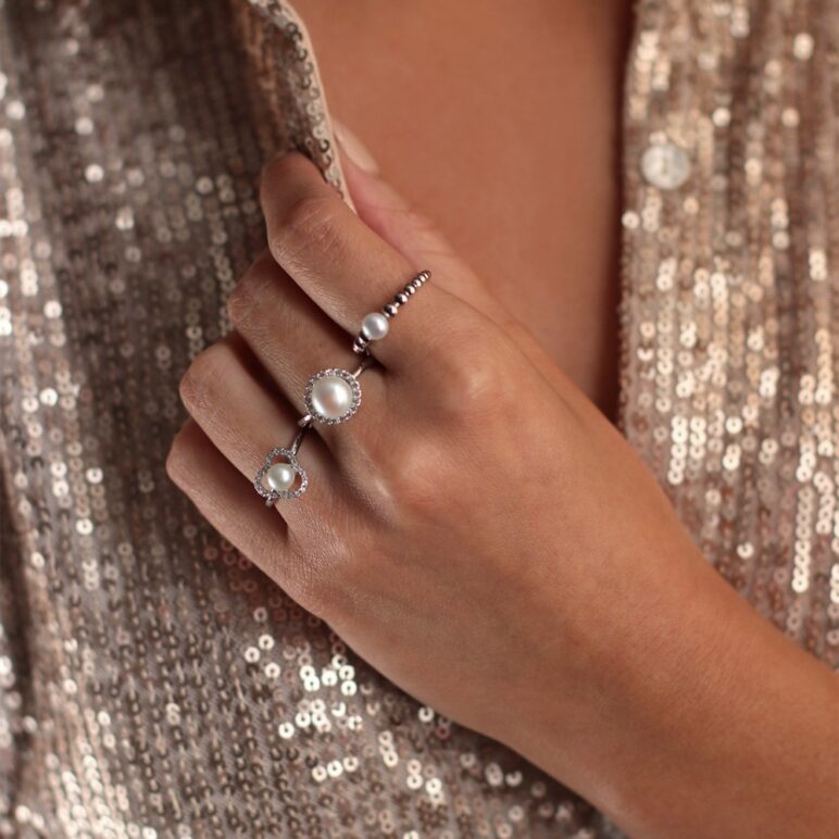 Woman wearing Jersey Pearl rings in sterling silver. Coast pearl ring, Amberley cluster pearl ring and Marette tau pearl ring.