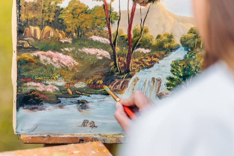Close up of a lady painting a forrest scene