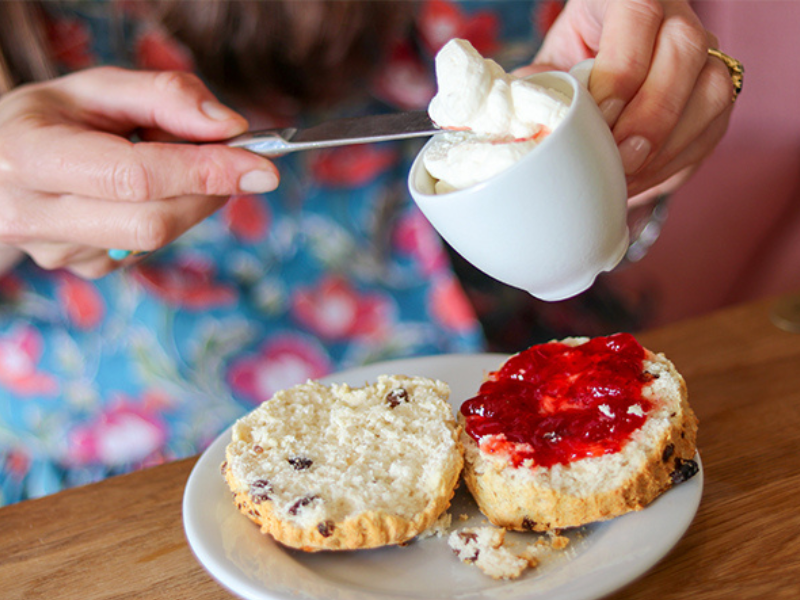 Woman adding cream to her scone