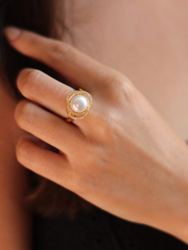 Woman wearing Marette altair pearl ring, white topaz stones hand set around a Freshwater pearl with yellow gold plated Sterling Silver.