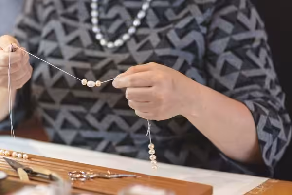 womans hands stringing pearls